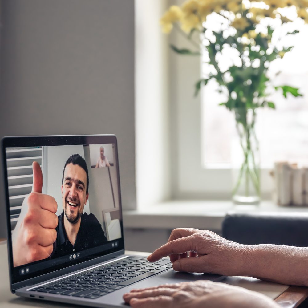 A retired old woman communicates via video call with her son, uses laptop, technology concept.
